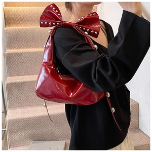 Detail of red patent leather shoulder bag with studded bow and silver rivets decoration