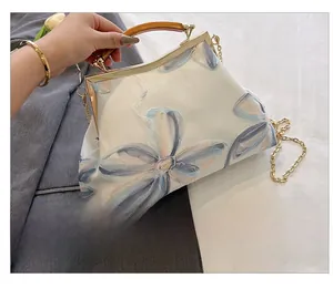 Rear view of white vintage clutch bag featuring delicate blue floral embroidery and chain