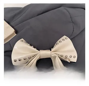 Detail of cream white leather handle with bow design and silver metal rivets