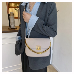 Close-up of beige lychee texture leather bag with gold chain and metal buckle detail