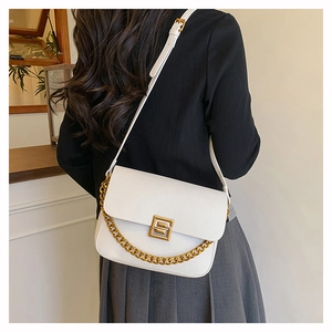 Detail shot of white lychee leather handbag with gold square buckle and chain strap