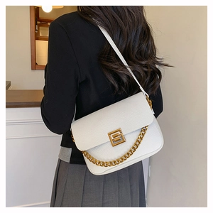 Close-up of white pebble leather bag with gold hardware and chain on a shoulder