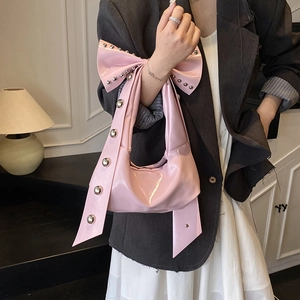 Pink patent leather hobo bag featuring oversized bow and metallic silver rivets