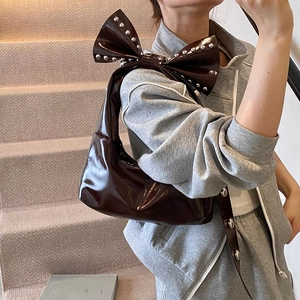 Fashionable dark brown patent leather shoulder bag with large bow and silver studs