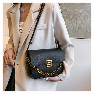Close-up of black pebbled leather handbag with gold square buckle and chunky metal chain