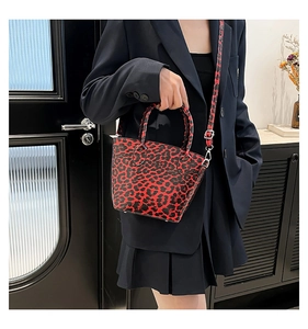 Detail of red leopard print bucket bag with detachable strap and leather texture