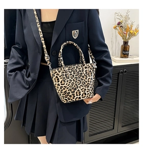 Detail of leopard print mini tote bag featuring dual handles and adjustable shoulder strap
