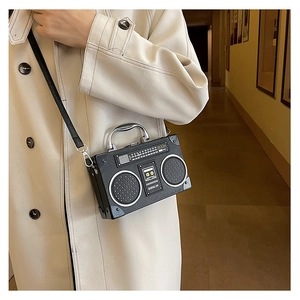 Retro radio-shaped black PU leather crossbody bag with silver handle worn over a trench coat