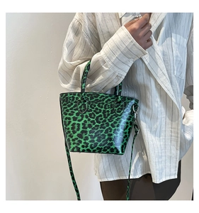 Borsa a secchiello verde leopardata indossata da modella con camicia a righe