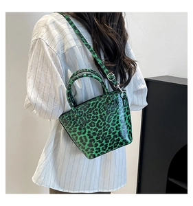 Detail of trendy green leopard print crossbody bag with glossy finish and top handles