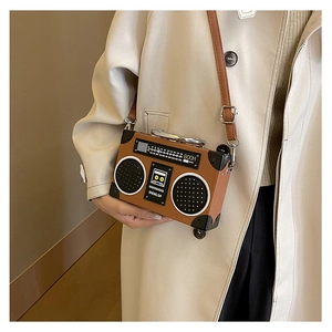 Brown vintage radio crossbody bag worn with a stylish trench coat over the shoulder