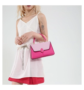 Detail einer pinken Kontrasttasche mit goldener Schließe von einem Model gehalten