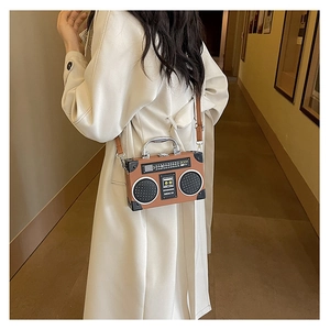 Detail view of radio-shaped retro crossbody bag worn by a model in a minimalist white coat