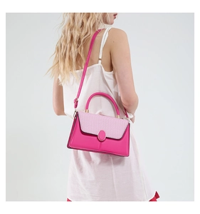 Detail of fuchsia shoulder bag featuring woven texture flap and metallic oval buckle