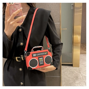 Detail of red vintage radio-shaped crossbody bag worn with a black outfit for contrast