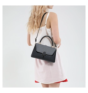 Detailed side view of a black and grey textured crossbody bag worn by a model