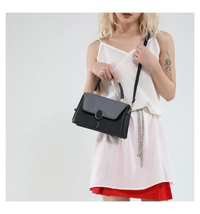 Detail shot of a minimalist black and grey patchwork small square handbag with gold buckle