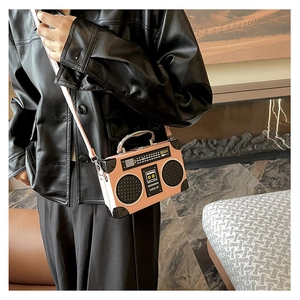 Detail of creative vintage radio shaped crossbody bag with metallic top handle and pink panels