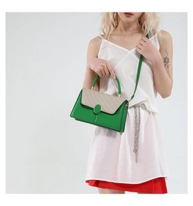 Close-up of green leather cross-body bag with beige straw texture flap and gold hardware