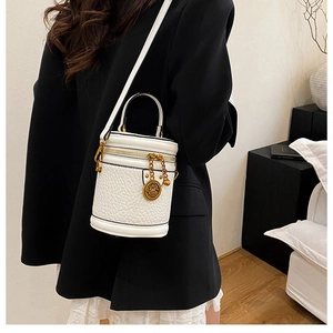Detail of white crocodile texture cylinder bucket bag with vintage gold emblem and strap