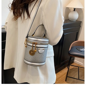 Detail of silver bucket bag showing faux crocodile texture and gold hardware on model