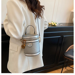 Detail of silver cylindrical bucket bag with lizard texture and gold hardware accents
