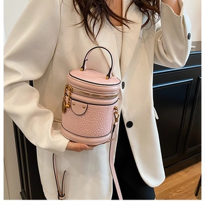 Detail of pink cylindrical bucket bag with embossed animal texture and gold hardware chain