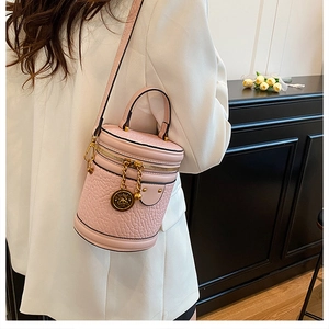 Close-up of pink ostrich texture bucket bag with gold hardware and top handle strap