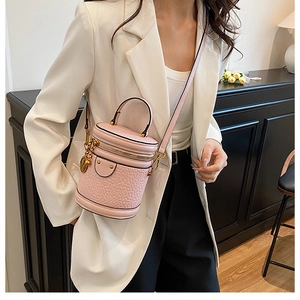 Pink cylinder bucket bag with embossed leather texture shown with a chic white blazer