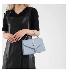 Light blue textured crossbody bag shown on a model with a black dress in a studio