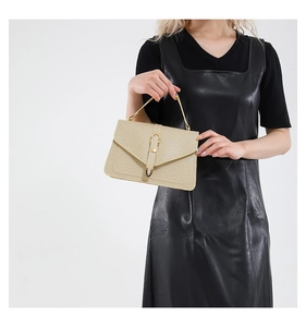 Detail of champagne gold textured handbag with metallic U-shaped buckle and envelope flap