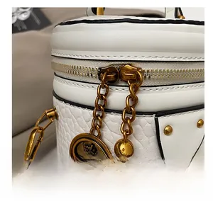 Close-up of white pebble leather bucket bag with gold zippers and crown charm details