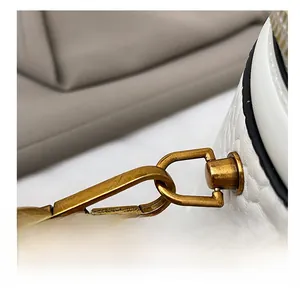 Detailed close-up of retro bronze metal hook on white lychee grain leather bucket bag