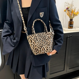 Chic leopard print handbag with black top handle and metal chain strap worn by a model