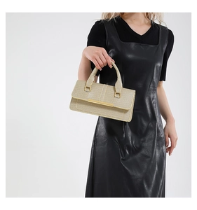 Detail van elegante beige getextureerde handtas met metalen staaf en stevig handvat