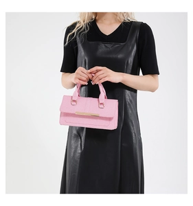 Detail van de roze handtas met krokodillenreliëf en goudkleurige metalen accenten