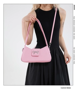 Close-up of pink baguette bag featuring a silver bow buckle and woven texture detail