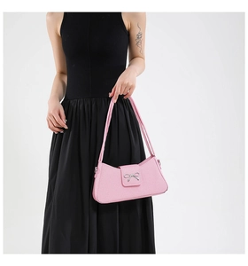 Détail du sac sous le bras rose avec nœud métallique argenté et texture cuir élégante