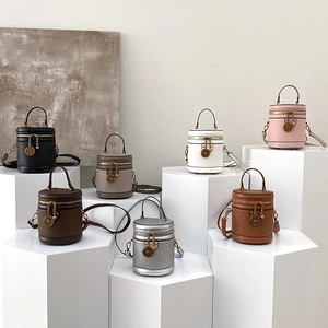 Fashionable cylinder bucket bags in various colors with litchi grain texture and metal charms