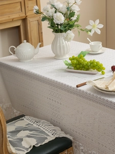 Detailed close-up of intricate lace edges and floral embroidery on a white vintage tablecloth
