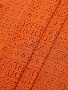 Macro shot of orange lace fabric with hollow geometric floral patterns for home decor