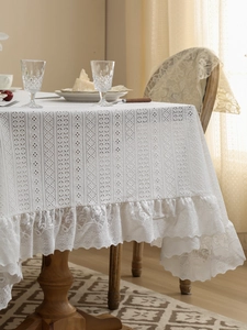 Detail of vintage white lace tablecloth featuring hollow embroidery and scalloped edges