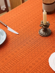 Macro shot of orange lace hollow tablecloth with retro geometric texture and fringed edges