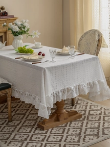 Close-up of elegant white lace tablecloth with intricate hollow embroidery and ruffled edges
