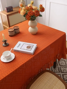 Detailed close-up of bright orange lace tablecloth with vintage floral hollow textures