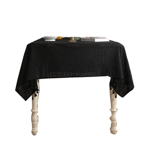 Elegant black hollow lace tablecloth with floral embroidery and tassel fringe on wooden table
