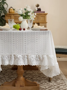 Close-up of elegant white lace tablecloth with geometric hollow patterns and ruffled edges