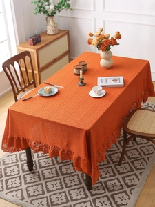 Detailed close-up of orange hollow lace tablecloth with delicate ruffle edge and floral texture