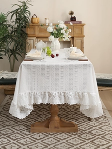 Detail of white crochet lace tablecloth featuring ruffled edges and hollowed patterns
