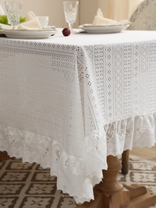 Macro detail of white lace tablecloth featuring diamond knit texture and scalloped edges